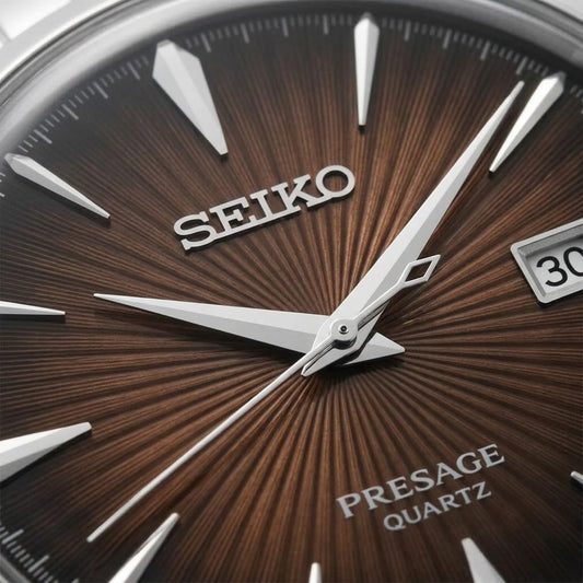Close-up of a Seiko Presage Quartz watch dial, showing a textured brown sunburst background, silver-tone hands and baton markers, and the Seiko brand name.